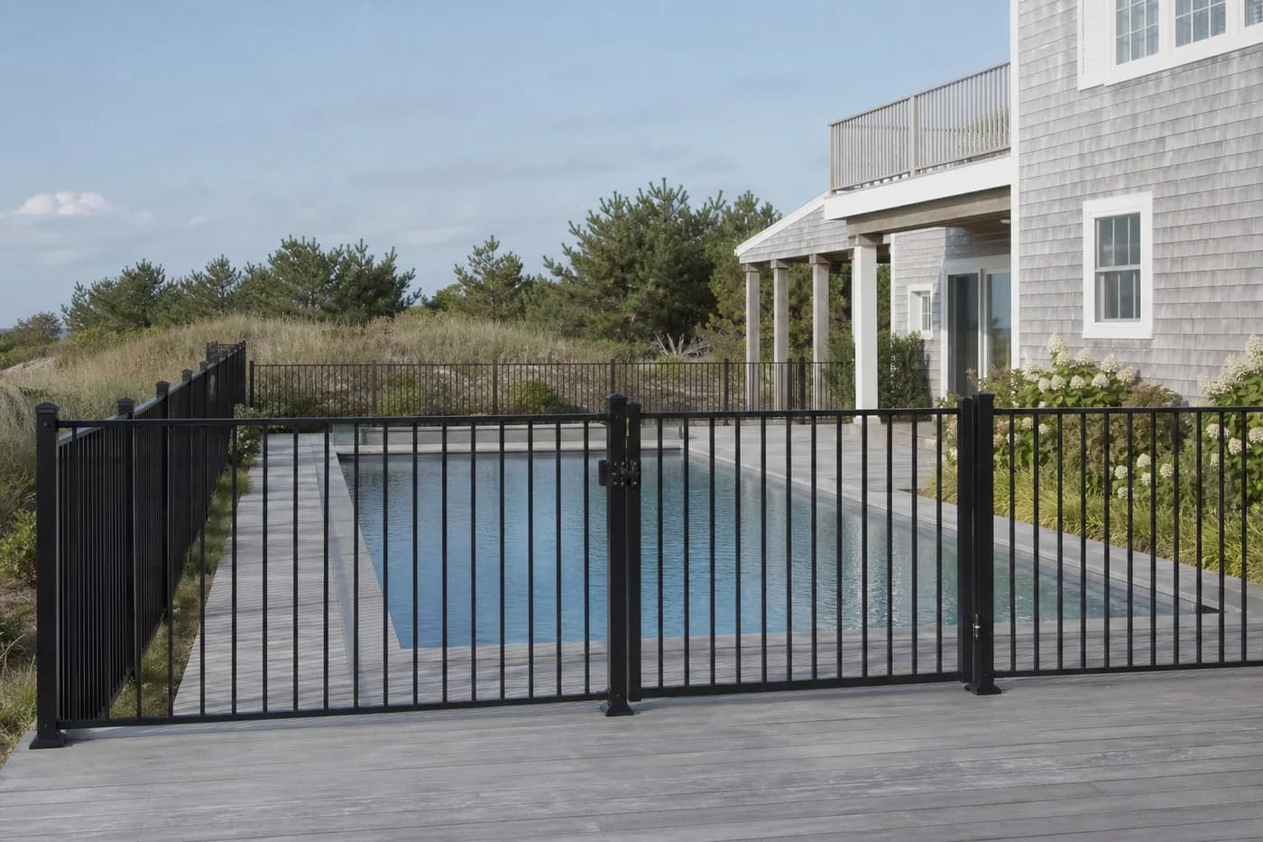 Black aluminum fence and gate enclosing a pool at a coastal gray-shingle home